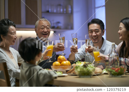 three generation asian family toasting while having dinner together 120379219