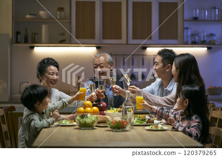 three generation asian family toasting while having dinner together three generation asian family toasting while having dinner together 120379265