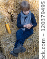 Little boy drinking tea sitting on bales of straw 120379495