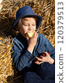 Boy sitting on the bales of straw and eating an apple. Healthy Eating 120379513