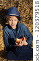 Boy sitting on the bales of straw and eating an apple. Healthy Eating 120379518