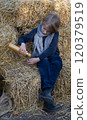Little boy pouring tea from thermos into cup sitting on the hay 120379519