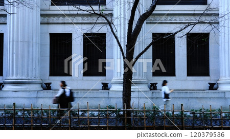 People walking on the sidewalk next to the Sumitomo Mitsui Banking Corporation Nihonbashi branch. People walking in front of a retro, stately stone building. 120379586