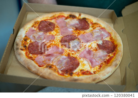 Pepperoni pizza in box with spicy salami sausage, mozzarella cheese, tomato sauce, just delivered,, black table background, top view Pepperoni pizza in box with spicy salami sausage, mozzarella cheese, tomato sauce, just delivered,, black table background, top view 120380041