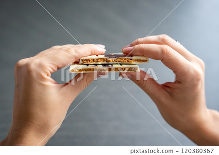 Piece of trend Dubai white chocolate with halva paste in woman hands. Confectionery handmade sweets at home in the kitchen.  120380367