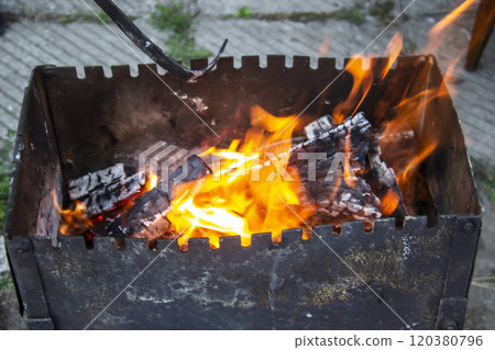 Barbecue grill mangal preparation with roaming fire outside building. Burns a firewood Barbecue grill mangal preparation with roaming fire outside building. Burns a firewood 120380796