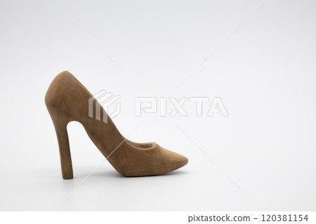 Women's shoe made from wood. A beautiful high-heeled wooden shoe against white background. Handmade shoe for use in female concept Women's shoe made from wood. A beautiful high-heeled wooden shoe against white background. Handmade shoe for use in female concept 120381154