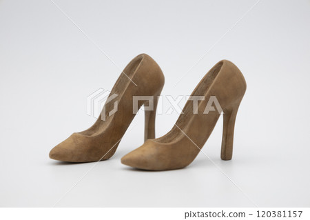 Pair of women's shoes made from wood. A beautiful high-heeled wooden shoes against white background. Handmade shoes for use in female concept Pair of women's shoes made from wood. A beautiful high-heeled wooden shoes against white background. Handmade shoes for use in female concept 120381157