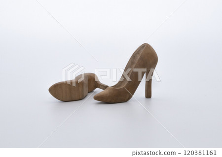 Pair of women's shoes made from wood. A beautiful high-heeled wooden shoes against white background. Handmade shoes for use in female concept Pair of women's shoes made from wood. A beautiful high-heeled wooden shoes against white background. Handmade shoes for use in female concept 120381161