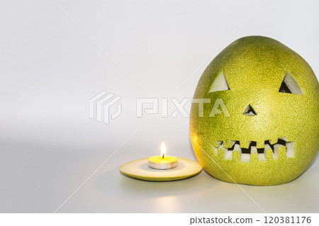 Scary face carved in pomelo fruit with candle in front isolated in gray background Scary face carved in pomelo fruit with candle in front isolated in gray background 120381176