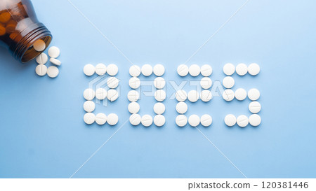 Happy New Year banner for medical theme. Number 2025 made by white pills spilling out of brown glass bottle on blue background. Creative idea for health care, medical and pharmacy concept. 120381446