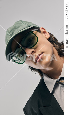 Close-up portrait of handsome young guy wearing style accessories, green baseball cap, and oversized green sunglasses 120381658