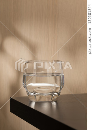 A clear glass of drinking water sits on a wooden table. 120381844