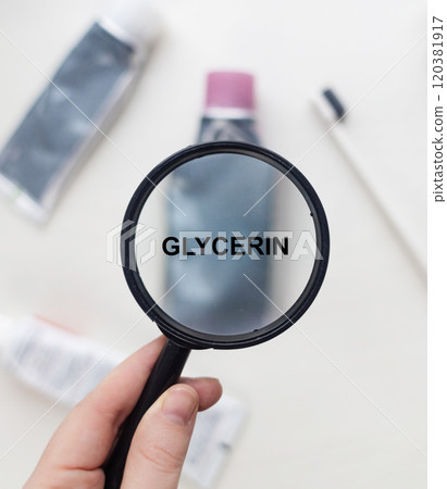 Glycerin in natural toothpaste. Magnifying glass is directed at a tube with a list of ingredients of a safe product. Safe toothpaste composition 120381917