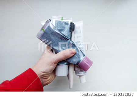 Woman holds many tubes of oral hygiene products in her hand. Using natural toothpaste with safe sweeteners and eco-friendly ingredients Woman holds many tubes of oral hygiene products in her hand. Using natural toothpaste with safe sweeteners and eco-friendly ingredients 120381923