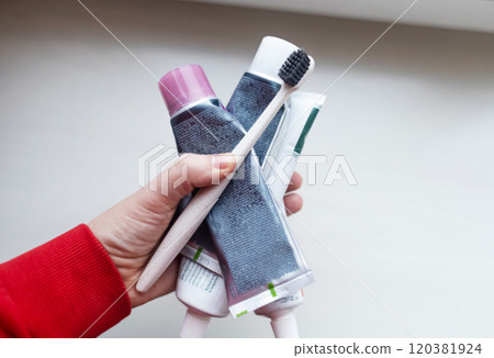 Woman holds many tubes of oral hygiene products in her hand. Using natural toothpaste with safe sweeteners and eco-friendly ingredients Woman holds many tubes of oral hygiene products in her hand. Using natural toothpaste with safe sweeteners and eco-friendly ingredients 120381924