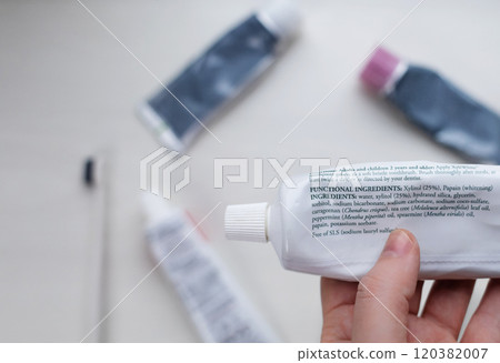 A tube of natural toothpaste with safe ingredients is lying on the table. List of natural components and ingredients. Use of ecological oral care products A tube of natural toothpaste with safe ingredients is lying on the table. List of natural components and ingredients. Use of ecological oral care products 120382007