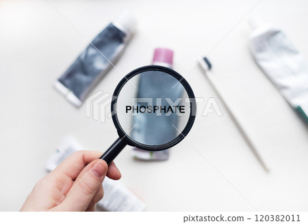 Phosphate in natural toothpaste. Magnifying glass is directed at a tube with a list of ingredients of a safe product. Safe toothpaste composition Phosphate in natural toothpaste. Magnifying glass is directed at a tube with a list of ingredients of a safe product. Safe toothpaste composition 120382011