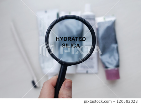 Hydrated silica in natural toothpaste. Magnifying glass is directed at a tube with a list of ingredients of a safe product. Safe toothpaste composition Hydrated silica in natural toothpaste. Magnifying glass is directed at a tube with a list of ingredients of a safe product. Safe toothpaste composition 120382028