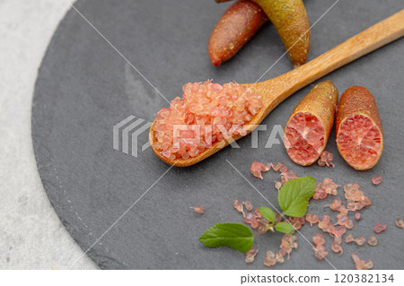 Finger lime on a black plate and spoon Finger lime flesh and cross section 120382134