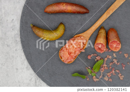 Finger lime on a black plate and spoon Finger lime flesh and cross section Finger lime on a black plate and spoon Finger lime flesh and cross section 120382141
