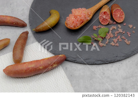 Finger lime on a black plate and spoon Finger lime flesh and cross section 120382143