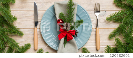 Christmas table place setting with christmas decor and plates, kine, fork and spoon. Christmas holiday background. Top view 120382601