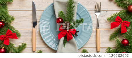 Christmas table place setting with christmas decor and plates, kine, fork and spoon. Christmas holiday background. Top view 120382602
