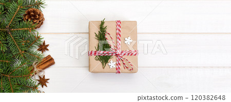 Christmas background with fir tree and gift box on wooden table. Top view with copy space for your design Christmas background with fir tree and gift box on wooden table. Top view with copy space for your design 120382648