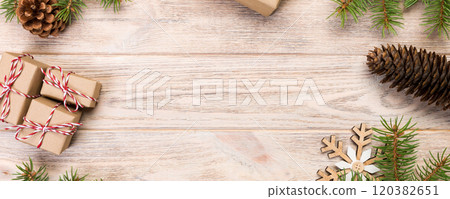 Christmas background with fir tree and gift box on wooden table. Top view with copy space for your design Christmas background with fir tree and gift box on wooden table. Top view with copy space for your design 120382651