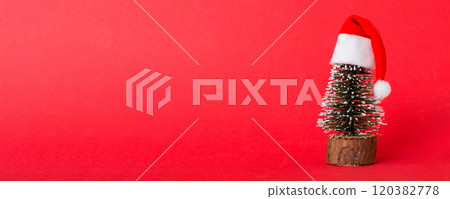 One small Christmas tree with santa hat on colored background. new year decoration with copy space 120382778