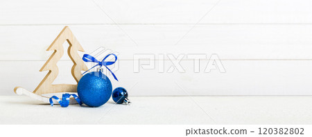 Christmas ball with decorative wooden tree on colored background. decoration bauble with ribbon bow with copy space 120382802