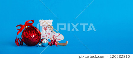Christmas ball with skates on colored background. decoration bauble with ribbon bow with copy space Christmas ball with skates on colored background. decoration bauble with ribbon bow with copy space 120382810