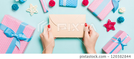 Top view of woman holding an envelope on blue background made of holiday decorations. Christmas time concept 120382844