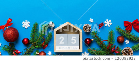 Christmas calendar 25 december. Christmas gift, fir branches, pine cones. Flat lay, top view. New Year decorations on a colored background 120382922