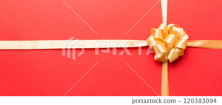 Top view of gold ribbon rolled and yellow bow isolated on colored background. Flat lay with copy space Top view of gold ribbon rolled and yellow bow isolated on colored background. Flat lay with copy space 120383094