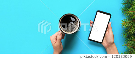 Female hands holding black mobile phone with blank white screen and mug of coffee. Mockup image with copy space. Top view on blue background, flat lay Female hands holding black mobile phone with blank white screen and mug of coffee. Mockup image with copy space. Top view on blue background, flat lay 120383099