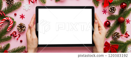 Christmas online shopping from home, female hands holding tablet pc with blank white display top view. woman hand holding tablet with blank screen, Christmas tree and gifts on background Christmas online shopping from home, female hands holding tablet pc with blank white display top view. woman hand holding tablet with blank screen, Christmas tree and gifts on background 120383192