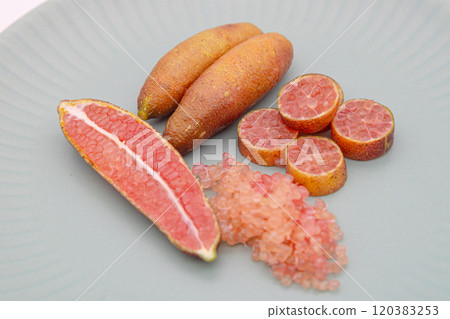 Finger limes served on a blue plate. Cross-section of finger lime and chunks of flesh 120383253