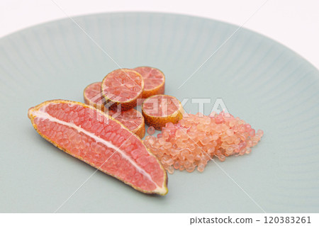 手指酸橙盛在藍色盤子上,是手指酸橙和果肉顆粒的橫截面。 手指酸橙盛在藍色盤子上,是手指酸橙和果肉顆粒的橫截面。 120383261
