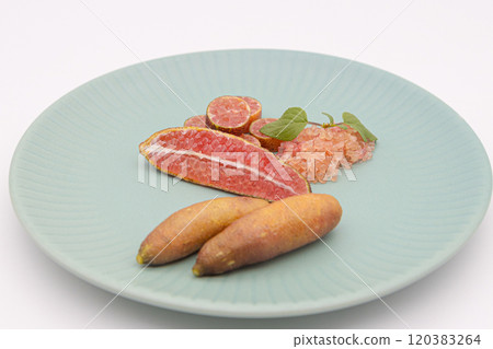 Finger limes served on a blue plate. Cross-section of finger lime and chunks of flesh 120383264