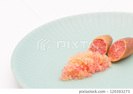 Finger limes served on a blue plate. Cross-section of finger lime and chunks of flesh 120383273