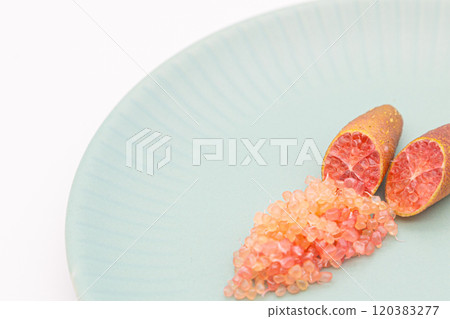 手指酸橙盛在藍色盤子上,是手指酸橙和果肉顆粒的橫截面。 手指酸橙盛在藍色盤子上,是手指酸橙和果肉顆粒的橫截面。 120383277