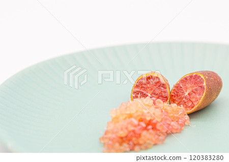 手指酸橙盛在藍色盤子上,是手指酸橙和果肉顆粒的橫截面。 手指酸橙盛在藍色盤子上,是手指酸橙和果肉顆粒的橫截面。 120383280