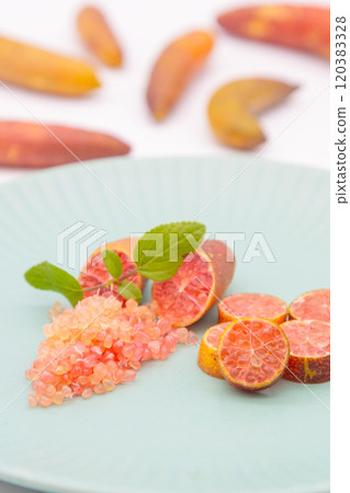 Finger limes served on a blue plate. Cross-section of finger lime and chunks of flesh 120383328
