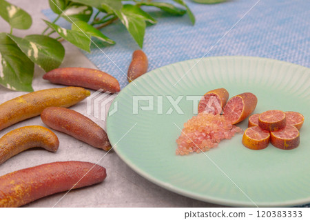 Finger limes served on a blue plate. Cross-section of finger lime and chunks of flesh 120383333
