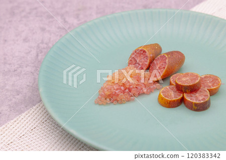 Finger limes served on a blue plate. Cross-section of finger lime and chunks of flesh Finger limes served on a blue plate. Cross-section of finger lime and chunks of flesh 120383342