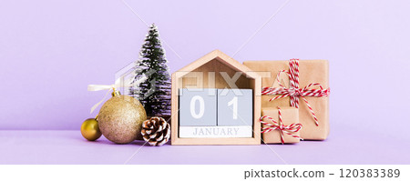 1 january. Christmas composition on colored background with a wooden calendar, with a gift box, toys, bauble copy space 120383389