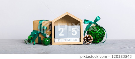 25 december. Christmas composition on colored background with a wooden calendar, with a gift box, toys, bauble copy space 120383843