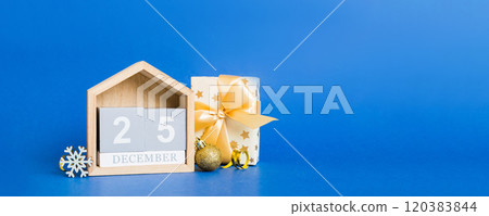 25 december. Christmas composition on colored background with a wooden calendar, with a gift box, toys, bauble copy space 120383844